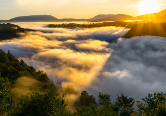 Cloud inversion above hills and mountain during colorful sunrise