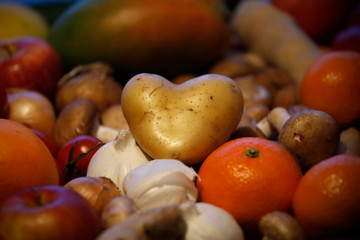 Herzförmige Kartoffel mit frischen bunten Obst und Gemüse