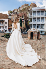Obraz premium incredibly charming bride poses for a photo in a sophisticated wedding dress walking along the pretty streets of the old Georgian city of Tbilisi