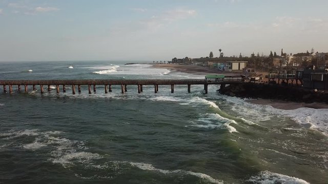 4K aerial drone video of Namibian Atlantic coastline, Swakopmund vintage buildings, town panorama, beach, old Jetty pier, landscape with ocean background of holiday resort at Namibia's west coast
