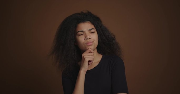Pensive african american girl thinking on isolated brown wall background
