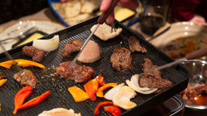 People grilling on an indoors electric grill and sharing food