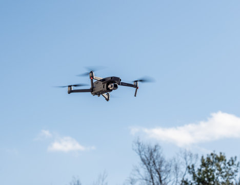 DJI Mavic Pro 2 drone flying above the camera against blue sky