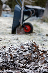 Gartenarbeit mit Laubhaufen, Schubkarre im Winter bei Eis und Schnee