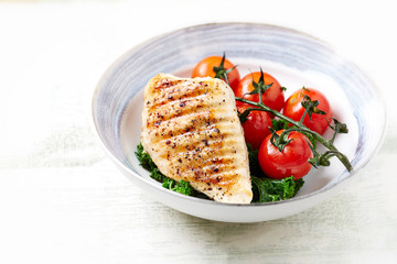 Grilled Chicken Breast with roasted Cherry Tomatoes. Bright wooden background. Close up. Copy space.