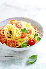 Spaghetti with cherry tomatoes and fresh oregano on bright wooden background. 