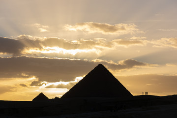 Obraz na płótnie Canvas Silhouette of Pyramid of Menkaure and several people in front of sunset in Giza