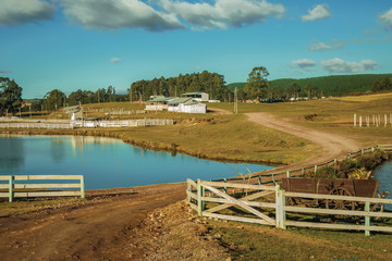 Fototapeta na wymiar Pretty farm with fences, livestock sheds and lake