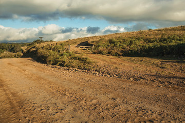 Wooden farm gate next to deserted dirt road