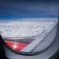 Airplane window with fluffy clouds