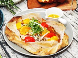 Baked fresh fish with vegetables and lemon in parcels