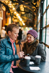 Caucasian couple sitting in a cafe drinking coffee and using a handheld smartphone device