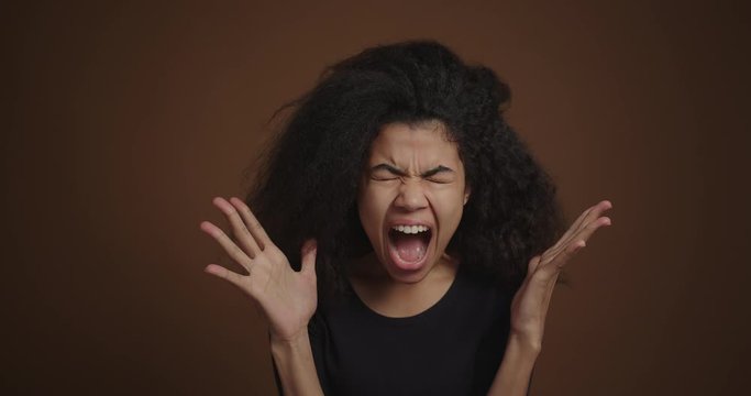 Portrait of african american girl shouting against the brown wall background