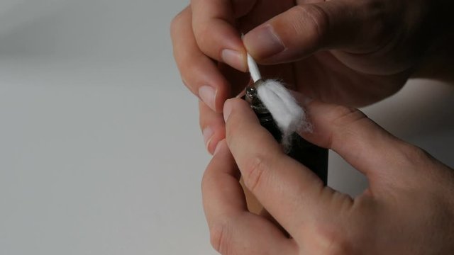 A man inserts new cotton wool in an electronic brown cigarette