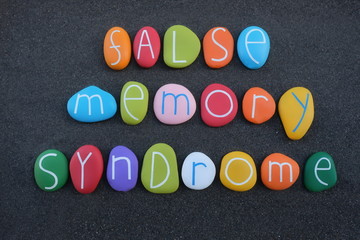 False memory syndrome text composed with creative painted stone letters over black volcanic sand