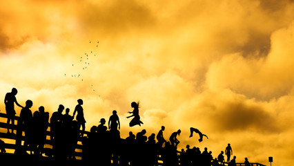 Fototapeta na wymiar silhouettes of people jumping of Beach Rd jaws bridge martha's vineyard Edgartown and Oak Bluffs sunset summer sky