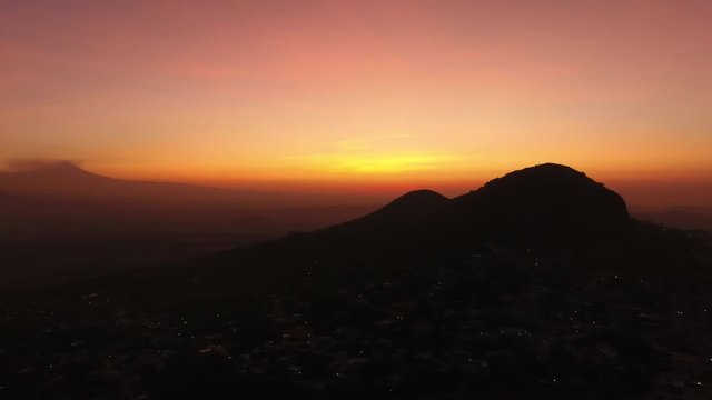 Wonderful aerial shot of beautiful orange sunrise over a little town, landscape behind the mountains and clouds