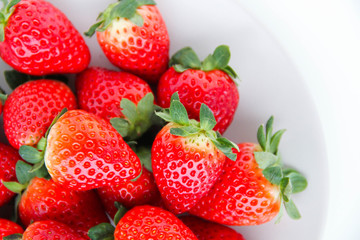 Fresh strawberries on a light grey plate, on a white background