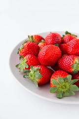 Fresh strawberries on a light grey plate, on a white background