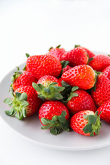 Fresh strawberries on a light grey plate, on a white background