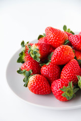 Fresh strawberries on a light grey plate, on a white background