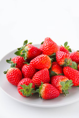 Fresh strawberries on a light grey plate, on a white background