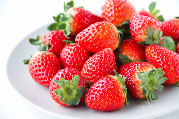 Fresh strawberries on a light grey plate, on a white background