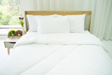 Obraz premium Bedroom decorated in minimal style, photograph of white pillows and wooden bed in bedroom with natural light from window.