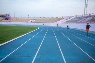 Running track in the stadium in the country. People running Look from behind