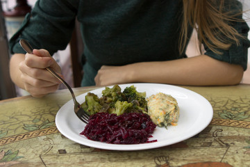 A girl eats the right, healthy food in a restaurant or cafe. Steamed broccoli, beets and steamed chicken.