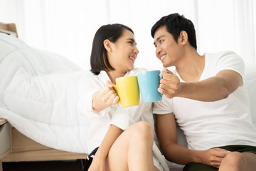 Asian young couple enjoying together with coffee in the morning in badroom, concept of leisure, couple, relationship and valentine. Photograph with copy space