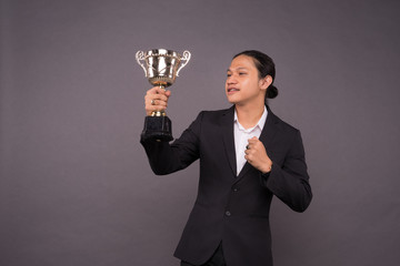 A young business man holding a gold trophy and celebrate his archivement.