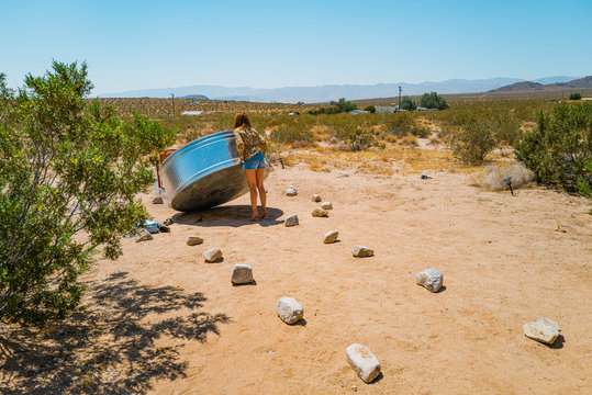 A woman in her twenties drains a stock tank basin in the desert of Joshua Tree, California