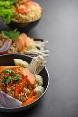 Noodles spicy in the Frying Pans with ingredients on black cement background.