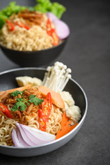 Noodles spicy in the Frying Pans with ingredients on black cement background.