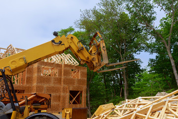 New construction home framing against a boom truck forklift