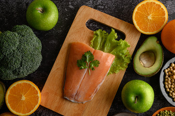 legumes, fruit, and Salmon fish pieces on a wooden chopping board.