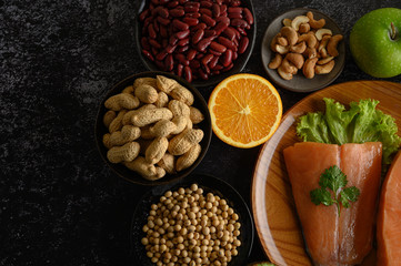 Legumes, fruit and salmon pieces on a wooden plate.