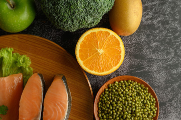 Legumes, fruit and salmon pieces on a wooden plate.