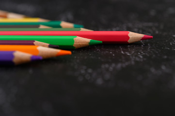 colorful crayon pencils with triangle shape on black background with copy space.