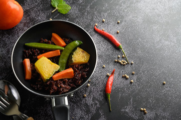 Purple rice berries with peas Pumpkin leaves, carrots and mint leaves in a frying pan