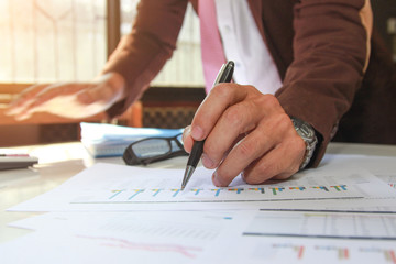 Concept Business holding pen pointing customer statistics On the desk with a graph in the office, Vintage, Sunset light.Selective Focus