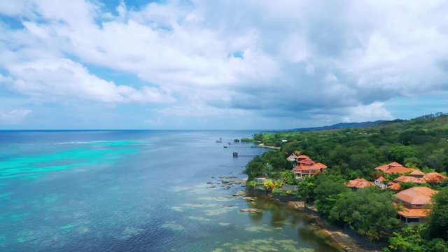 Aerial over ocean reef along beach and expensive real estate, Roatan