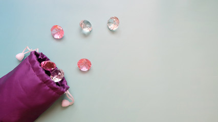 Faux pink and clear gems scattered out of a purple string pouch.