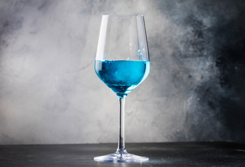 Exotic blue wine, trendy non-classical drink in wine glass on gray background