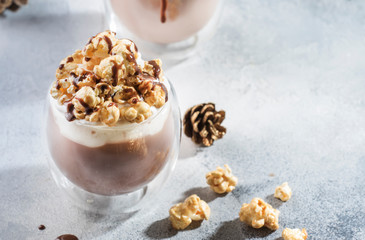 Cold chocolate dessert with whipped cream, popcorn and caramel topping in glasses on beige background, place for text