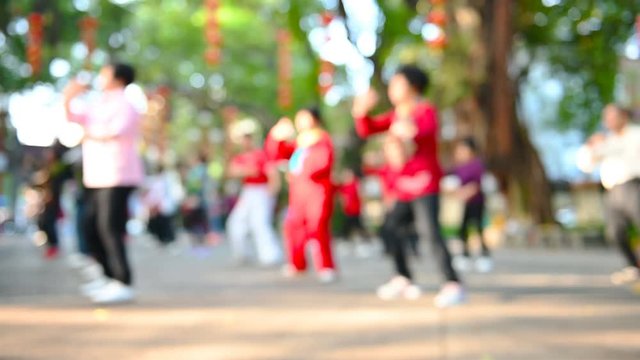 elder Chinese people doing Tai Ji exercise in a park in the morning at blurred focus as background