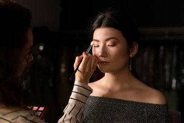 Make-up artist makes make-up asian model, eyeshadow applied with brush, close-up