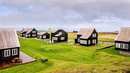 Fototapeta na wymiar A small community of black wooden Icelandic holiday homes, which all have the same exterior design elements, on the coast of the Atlantic Ocean.