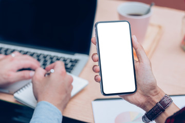 Mockup image blank white screen cell phone.man hand holding texting using mobile on desk at office.background empty space for advertise text.people contact marketing business,technology 